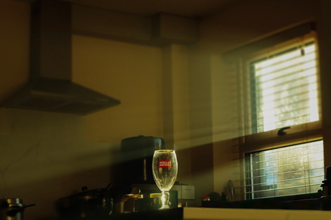 A wine glass sits on a counter near a window.