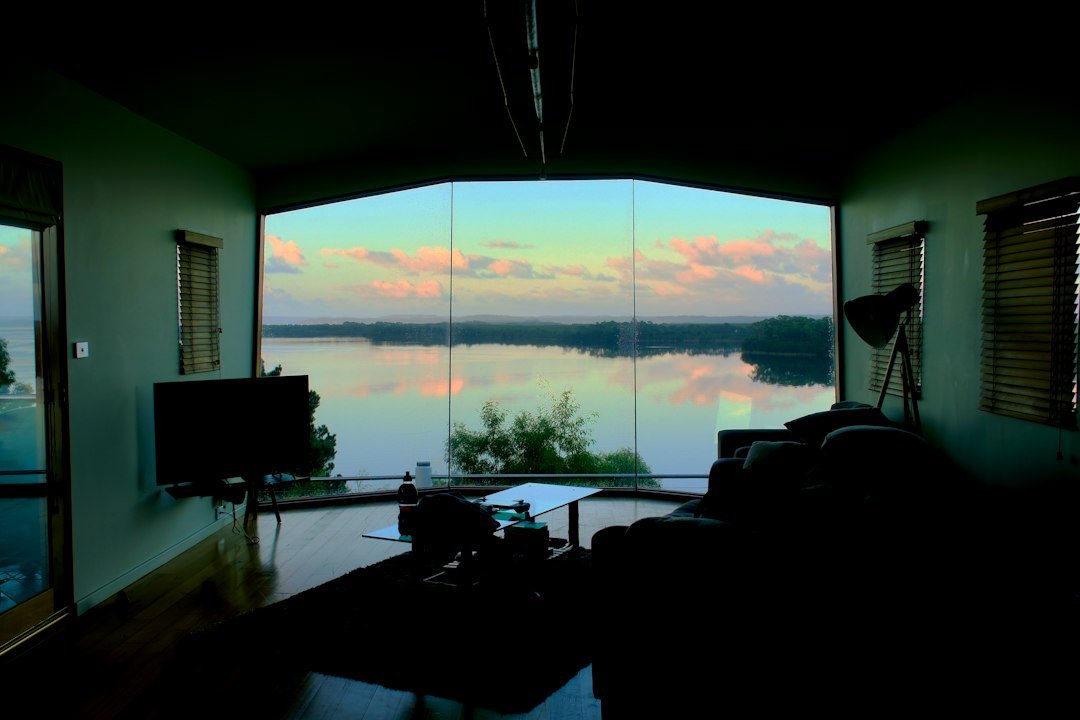 Living room with large window overlooking lake at sunset